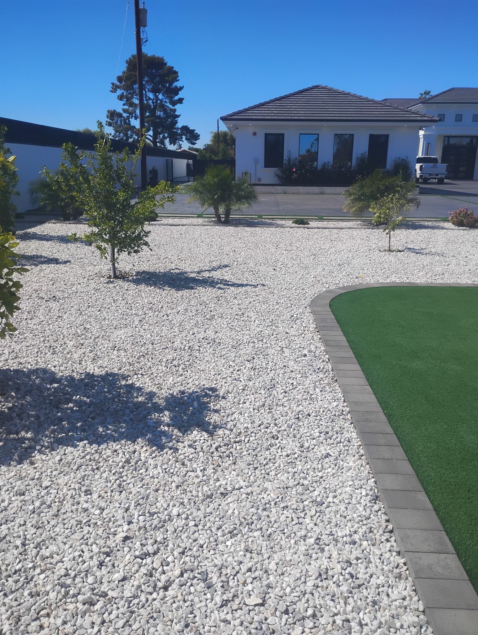 Front yard with white rock, artificial turf border, and new planting