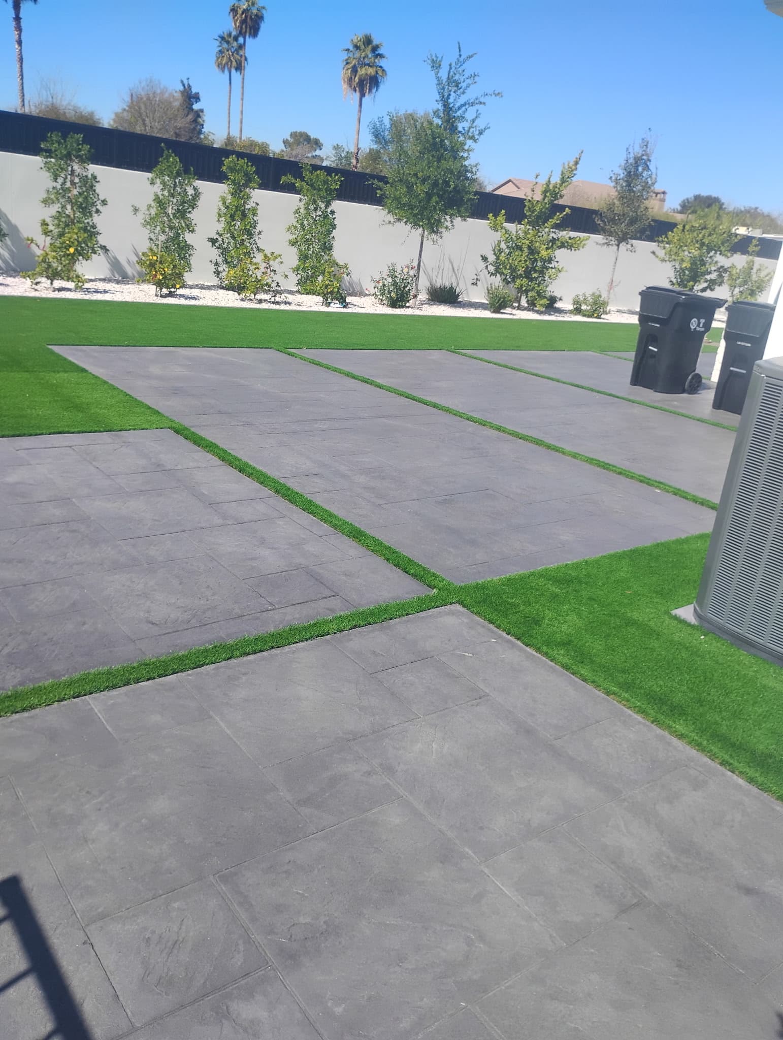 Completed backyard with gray paver grid and artificial turf